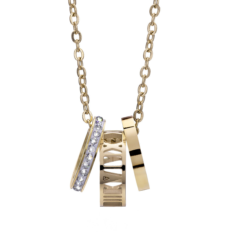 Vergoldete Halskette mit drei modernen Anhängern – ein Ring mit Kristallbesatz, ein filigran ausgeschnittener Ring und ein schlichter polierter Ring.