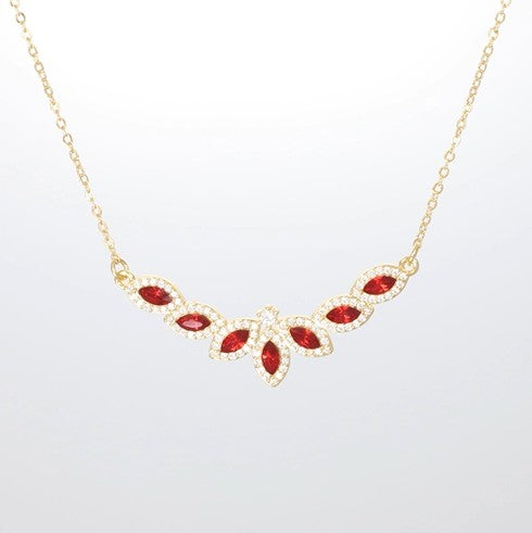 Halskette mit funkelndem Blütenanhänger aus roten Kristallen in goldfarbener Fassung.