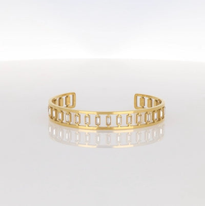 Armreif in goldfarbener Optik mit rechteckigen, klaren Kristallen in gleichmäßigem Muster.