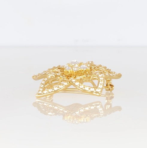 Goldene Blütenbrosche mit filigranem Muster, mit Swarovski® Kristallen verziert.
